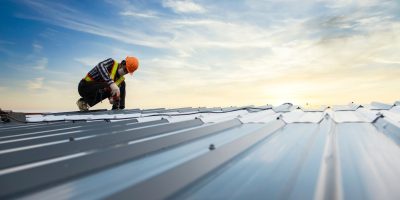 Builders in work clothes install new roofing tools, roofing tools, electric drill and use them on new wooden roofs with metal sheets