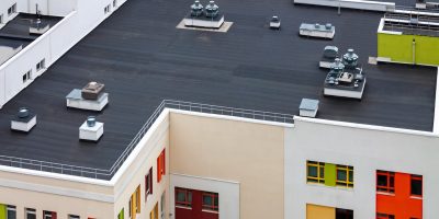 Top view dark flat roof with air conditioners and hydro insulation membranes modern apartment building residential area.